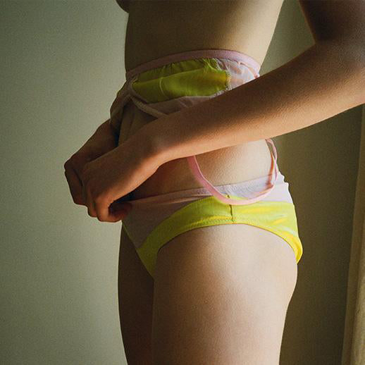 Closeup of woman wearing a yellow and pink bra and panty set